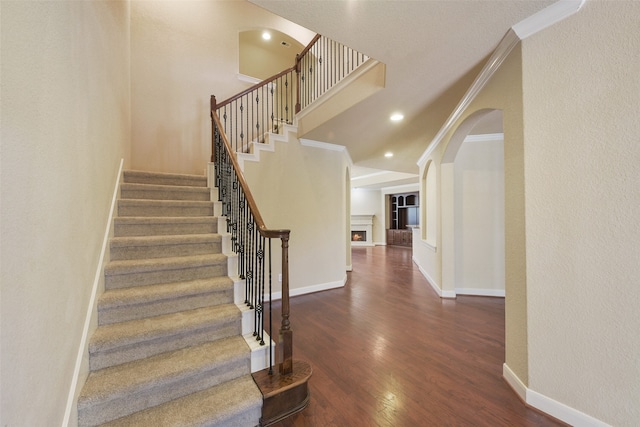 staircase featuring wood-type flooring and ornamental molding