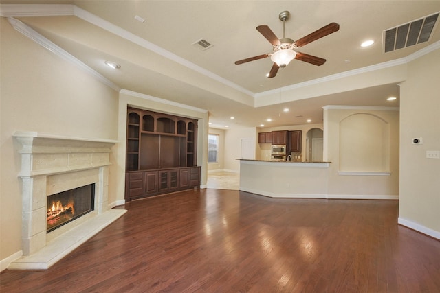 unfurnished living room featuring ceiling fan, crown molding, dark wood-type flooring, and a high end fireplace