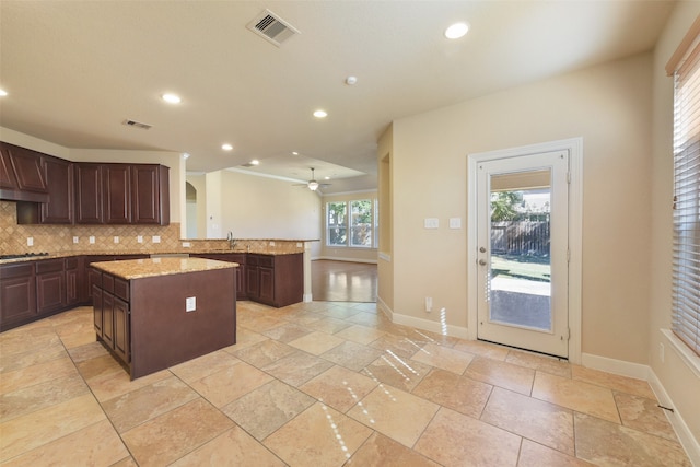 kitchen with sink, decorative backsplash, ceiling fan, a kitchen island, and kitchen peninsula