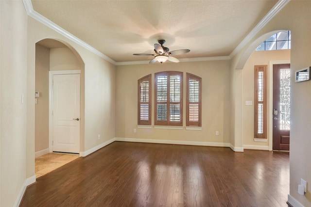 spare room featuring crown molding, plenty of natural light, and dark wood-type flooring