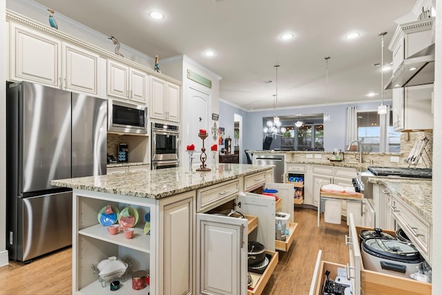 kitchen with light wood-type flooring, kitchen peninsula, hanging light fixtures, and appliances with stainless steel finishes