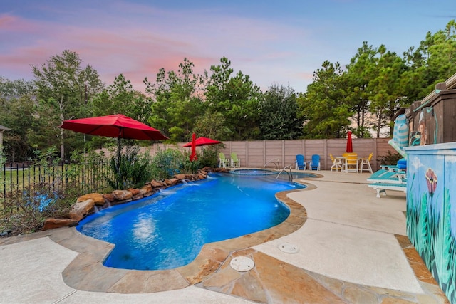 pool at dusk featuring pool water feature, an in ground hot tub, and a patio