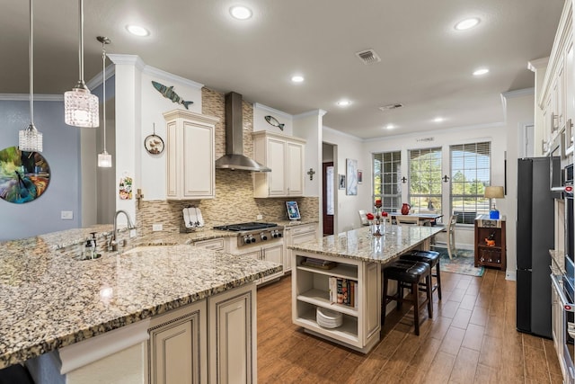 kitchen featuring light stone counters, dark wood-type flooring, sink, wall chimney range hood, and hanging light fixtures