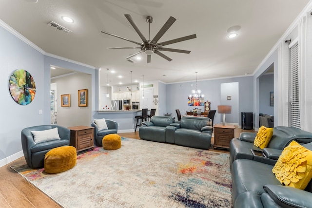 living room featuring ceiling fan with notable chandelier, hardwood / wood-style flooring, and crown molding