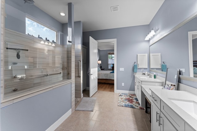 bathroom with a tile shower, vanity, and tile patterned floors