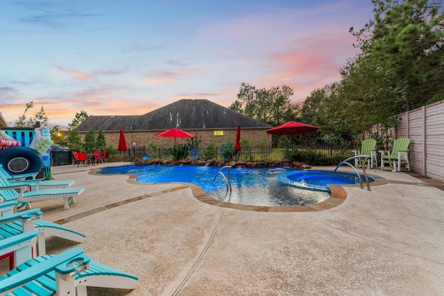 pool at dusk featuring an in ground hot tub, a patio, and pool water feature