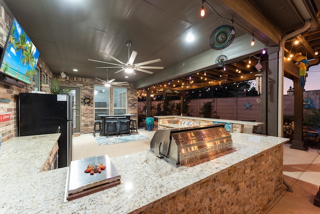 view of patio / terrace with exterior kitchen, ceiling fan, and a bar