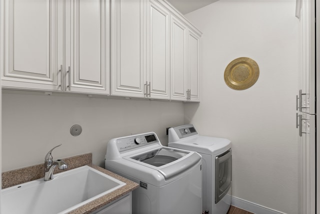 laundry room with cabinets, independent washer and dryer, hardwood / wood-style flooring, and sink