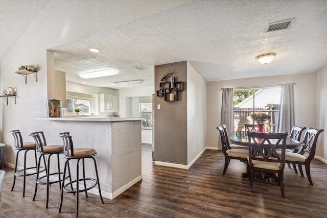 kitchen featuring a textured ceiling, kitchen peninsula, and dark hardwood / wood-style floors