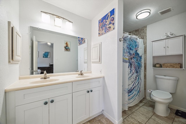 bathroom with a textured ceiling, toilet, tile patterned floors, walk in shower, and vanity