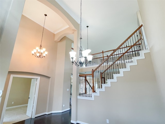 stairway with a notable chandelier, a towering ceiling, and ornamental molding