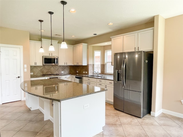 kitchen featuring white cabinets, stainless steel appliances, sink, and a kitchen island