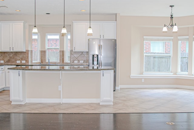 kitchen with a center island, white cabinetry, decorative light fixtures, and dark stone countertops