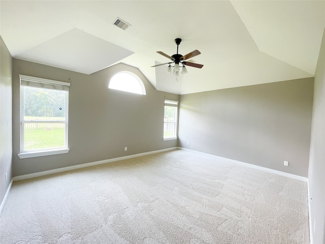 empty room featuring ceiling fan, vaulted ceiling, and light colored carpet