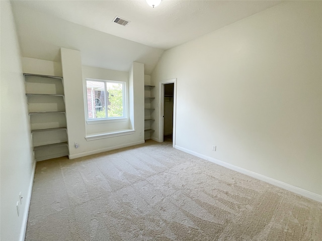 unfurnished bedroom with light carpet and lofted ceiling