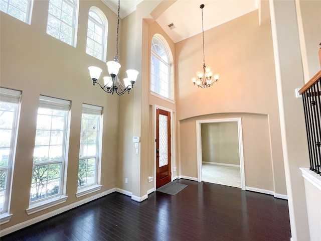 foyer entrance with crown molding, a high ceiling, a chandelier, and dark hardwood / wood-style floors