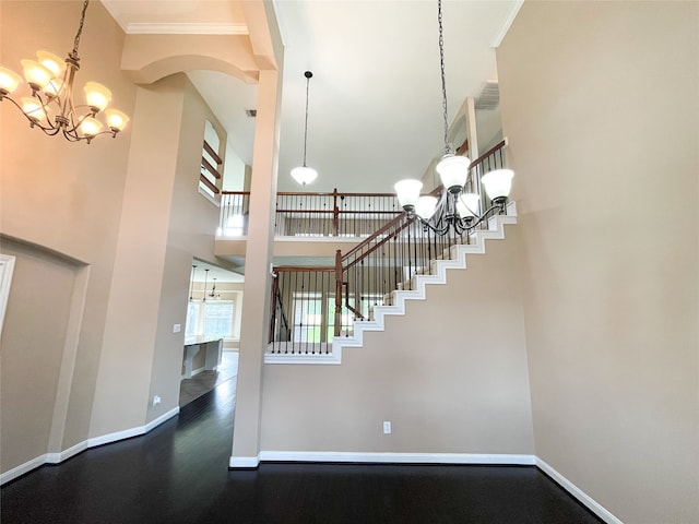 stairs with crown molding, a towering ceiling, and a chandelier