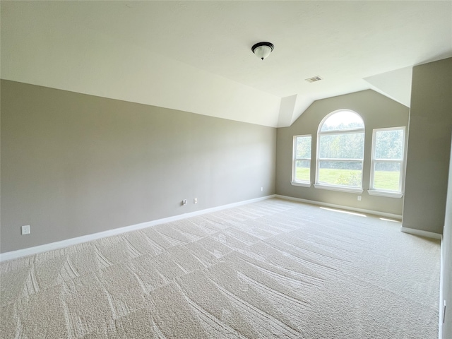 carpeted spare room with vaulted ceiling