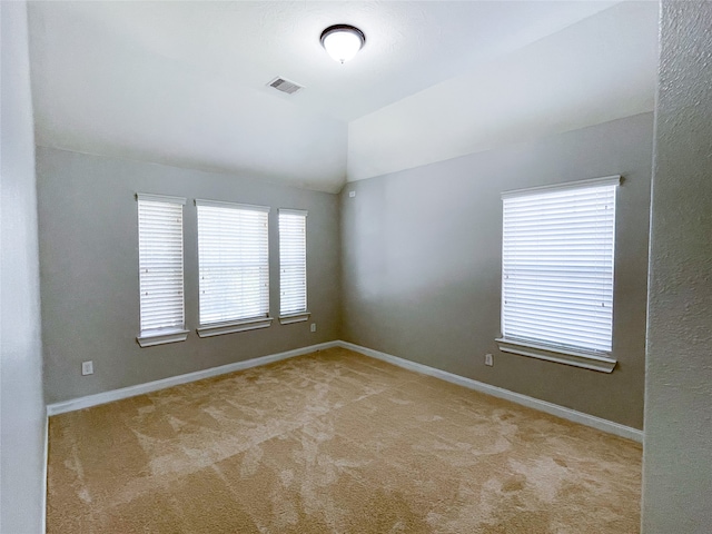 unfurnished room with lofted ceiling, a healthy amount of sunlight, and light colored carpet