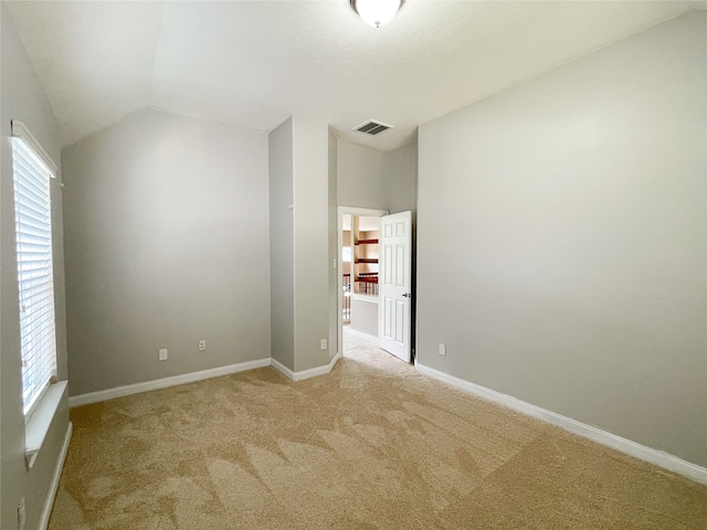 spare room with vaulted ceiling and light colored carpet