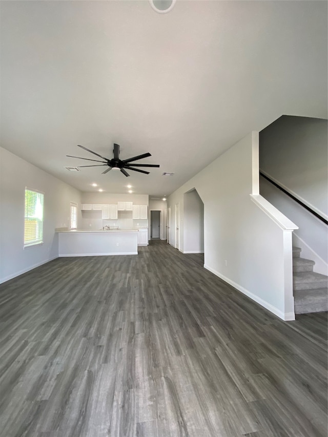 unfurnished living room with dark hardwood / wood-style floors and ceiling fan