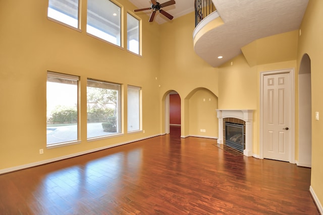 unfurnished living room featuring a towering ceiling, a wealth of natural light, and dark hardwood / wood-style floors