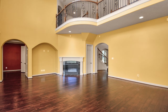 unfurnished living room featuring a towering ceiling, dark wood-type flooring, and a fireplace