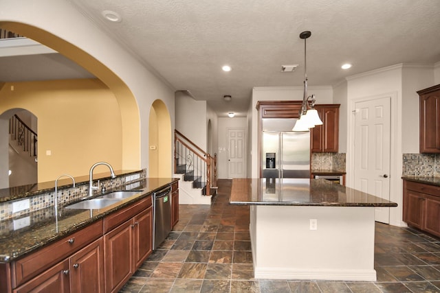 kitchen featuring a sink, dark stone countertops, stainless steel appliances, tasteful backsplash, and a kitchen island
