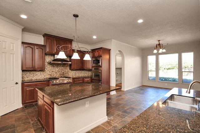 kitchen featuring appliances with stainless steel finishes, arched walkways, a sink, under cabinet range hood, and stone tile floors