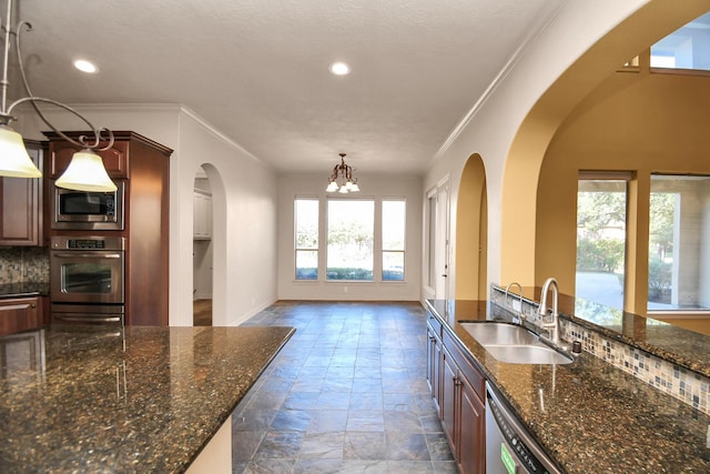 kitchen with crown molding, stone tile floors, arched walkways, a sink, and appliances with stainless steel finishes