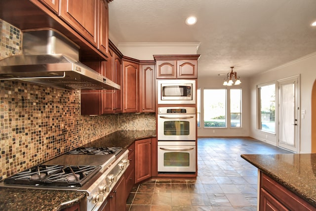 kitchen featuring appliances with stainless steel finishes, dark stone countertops, ornamental molding, and tasteful backsplash