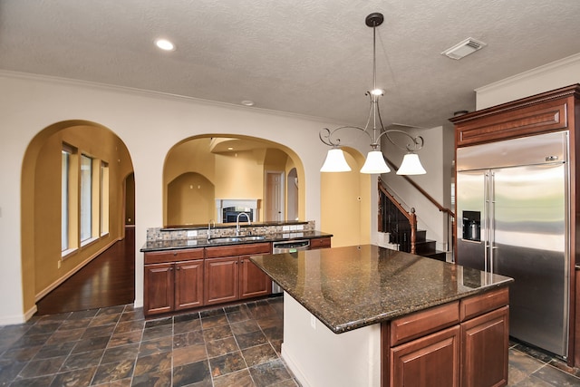 kitchen with sink, hanging light fixtures, stainless steel appliances, and a textured ceiling