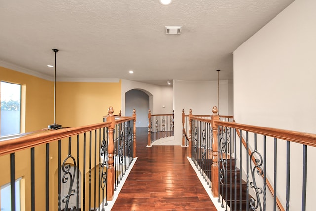 corridor featuring crown molding, a textured ceiling, and dark hardwood / wood-style floors