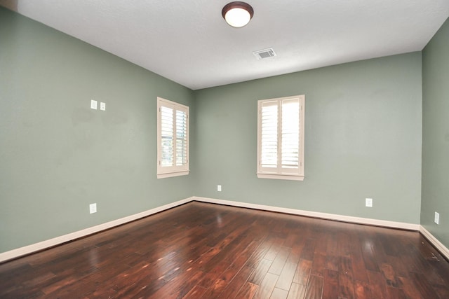 spare room featuring wood-type flooring, baseboards, and visible vents