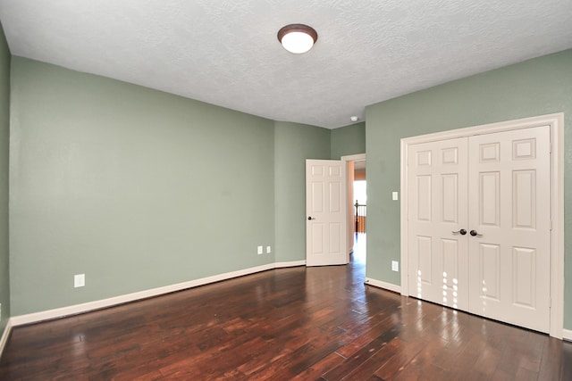 unfurnished bedroom with a textured ceiling, dark hardwood / wood-style floors, and a closet