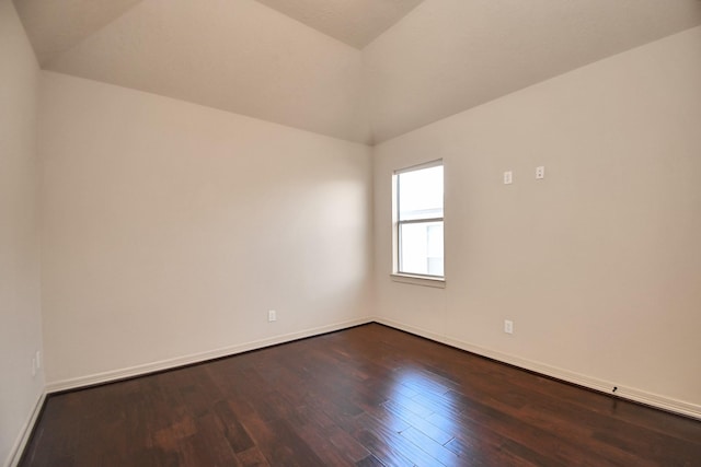 spare room featuring baseboards, vaulted ceiling, and dark wood-style floors
