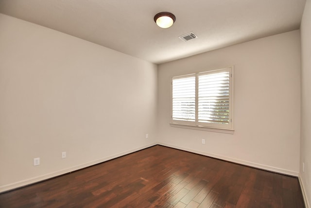 spare room with visible vents, dark wood finished floors, and baseboards