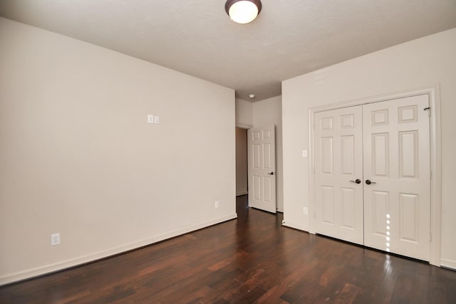 unfurnished bedroom featuring dark wood-style flooring, baseboards, and a closet