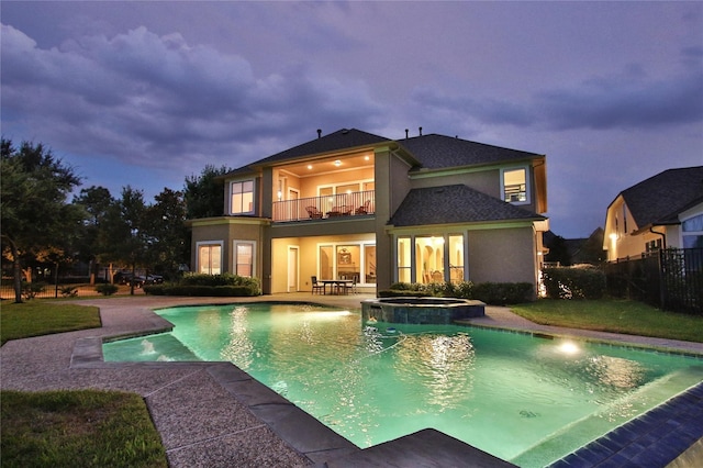 rear view of property with a pool with connected hot tub, a patio area, fence, a balcony, and stucco siding