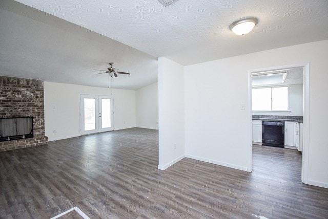 unfurnished living room with a wealth of natural light, ceiling fan, a fireplace, and dark hardwood / wood-style flooring