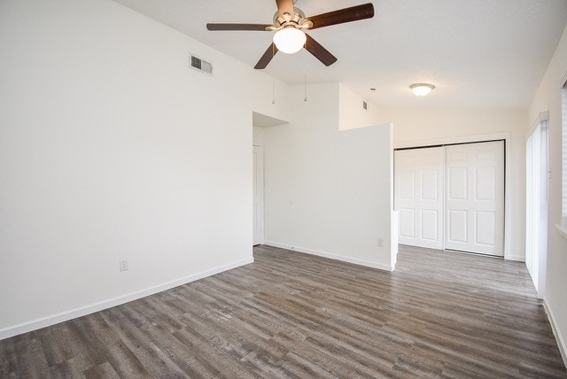 unfurnished bedroom with a closet, ceiling fan, lofted ceiling, and dark hardwood / wood-style flooring