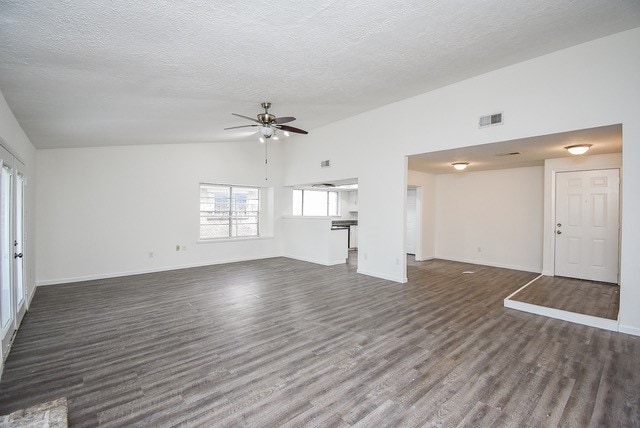 unfurnished living room featuring a textured ceiling, vaulted ceiling, dark hardwood / wood-style floors, and ceiling fan