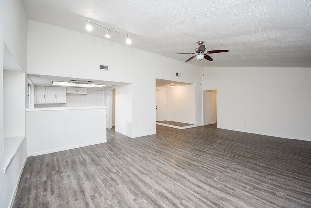 unfurnished living room featuring a textured ceiling, high vaulted ceiling, light hardwood / wood-style floors, and ceiling fan