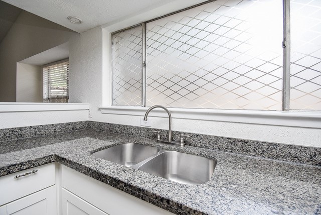 kitchen with white cabinetry, sink, and dark stone counters