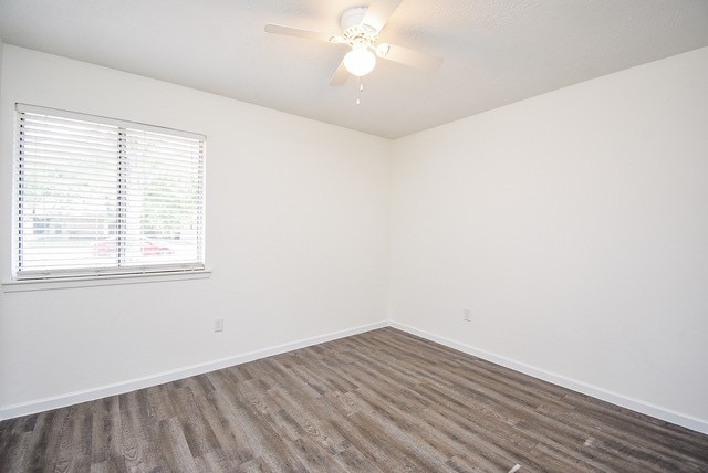 empty room featuring dark wood-type flooring and ceiling fan