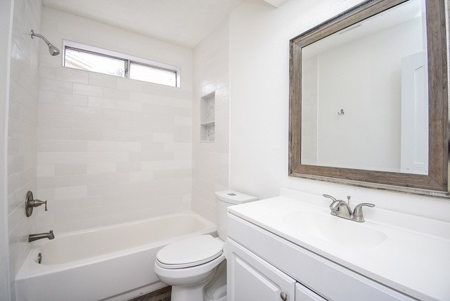 full bathroom featuring toilet, tiled shower / bath, and vanity