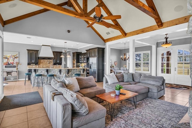 living room with beamed ceiling, light tile patterned flooring, ceiling fan with notable chandelier, and high vaulted ceiling