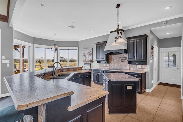 kitchen with tasteful backsplash, a center island with sink, light tile patterned flooring, pendant lighting, and sink