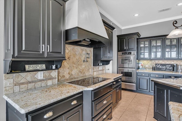 kitchen featuring wall chimney exhaust hood, crown molding, light tile patterned flooring, black electric stovetop, and double oven