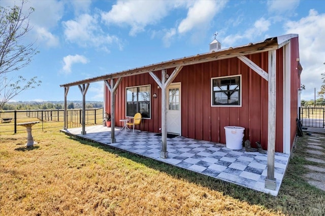 back of house featuring a yard, a patio area, and a rural view